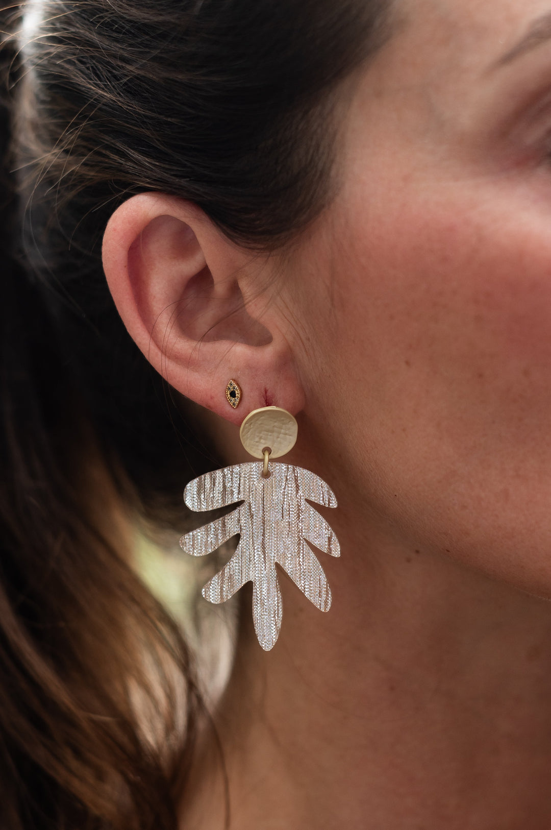 Close-up of a woman wearing a leaf-shaped earring.