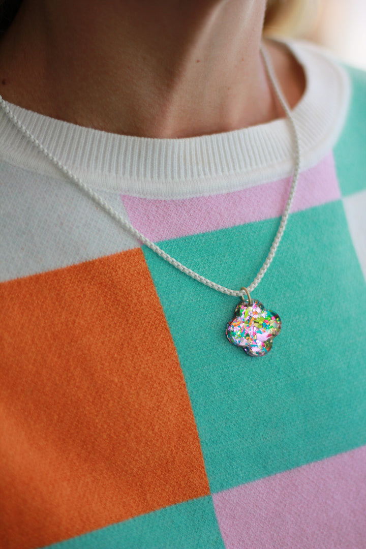 Necklace with a colorful heart pendant on a checkered fabric background